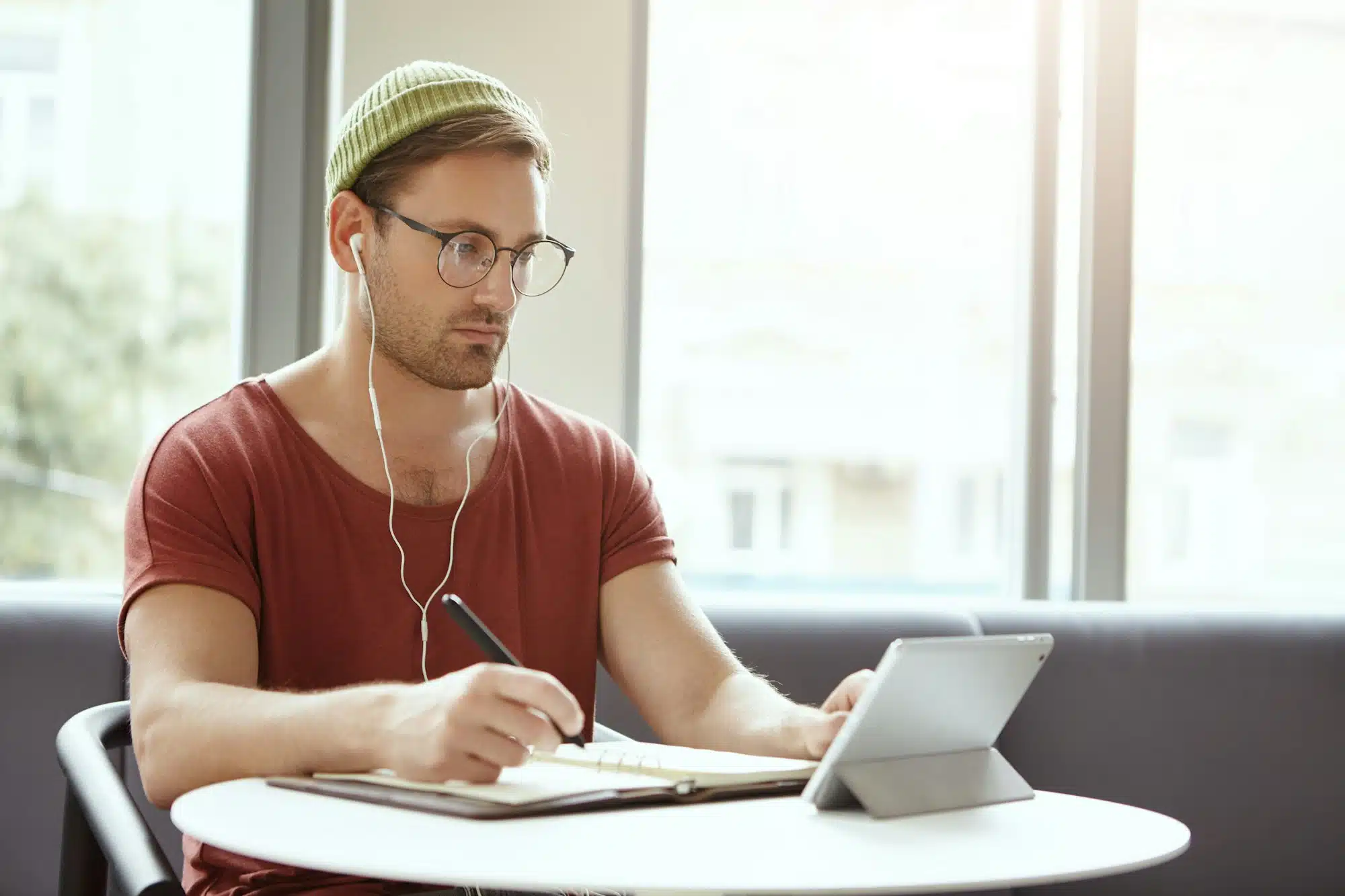 People, learning and education concept. Attractive bearded male college student taking notes down fr